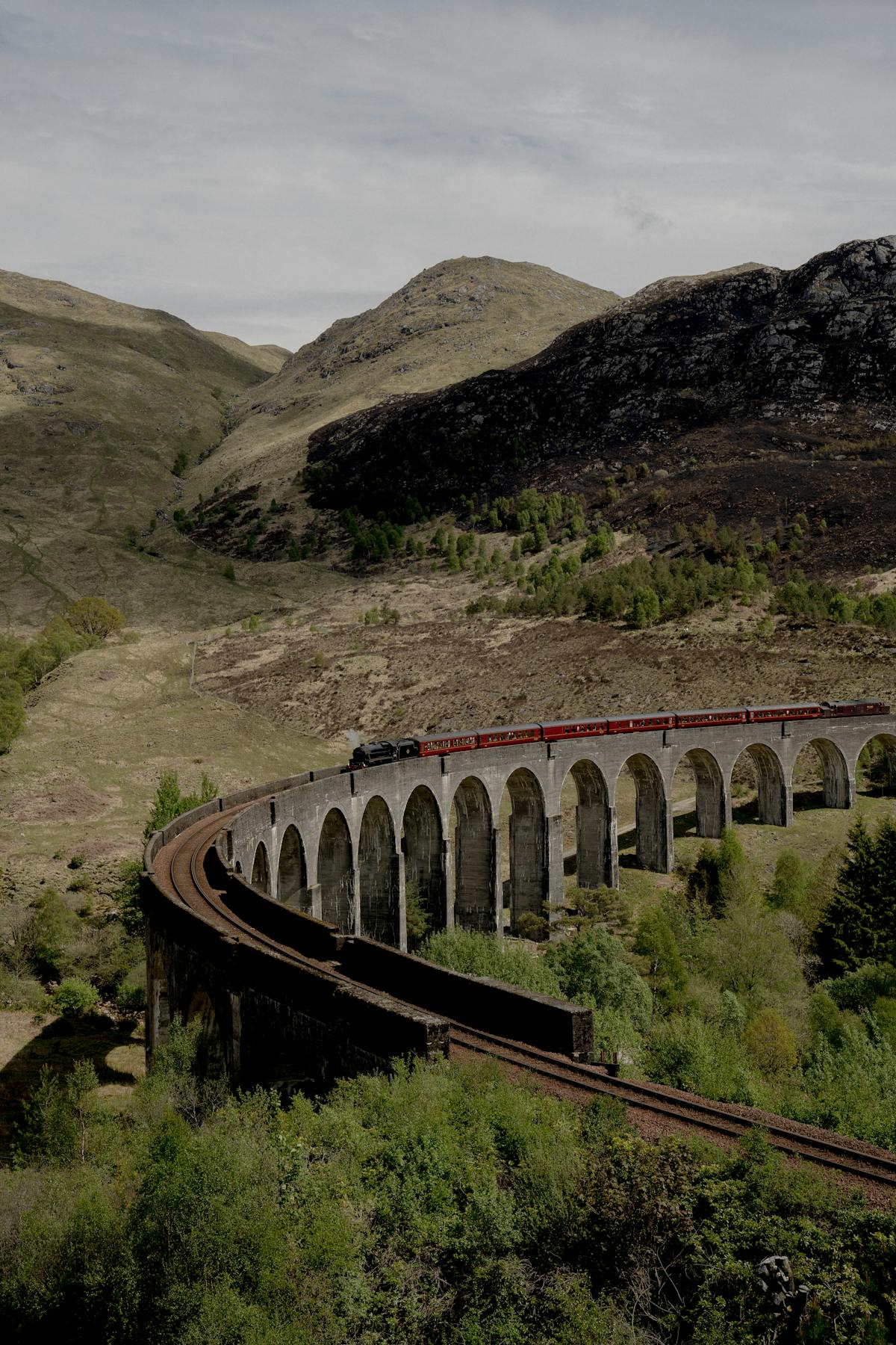 The Jacobite steam train crossing Glenfinnan Viaduct with steam billowing against the Highland scenery